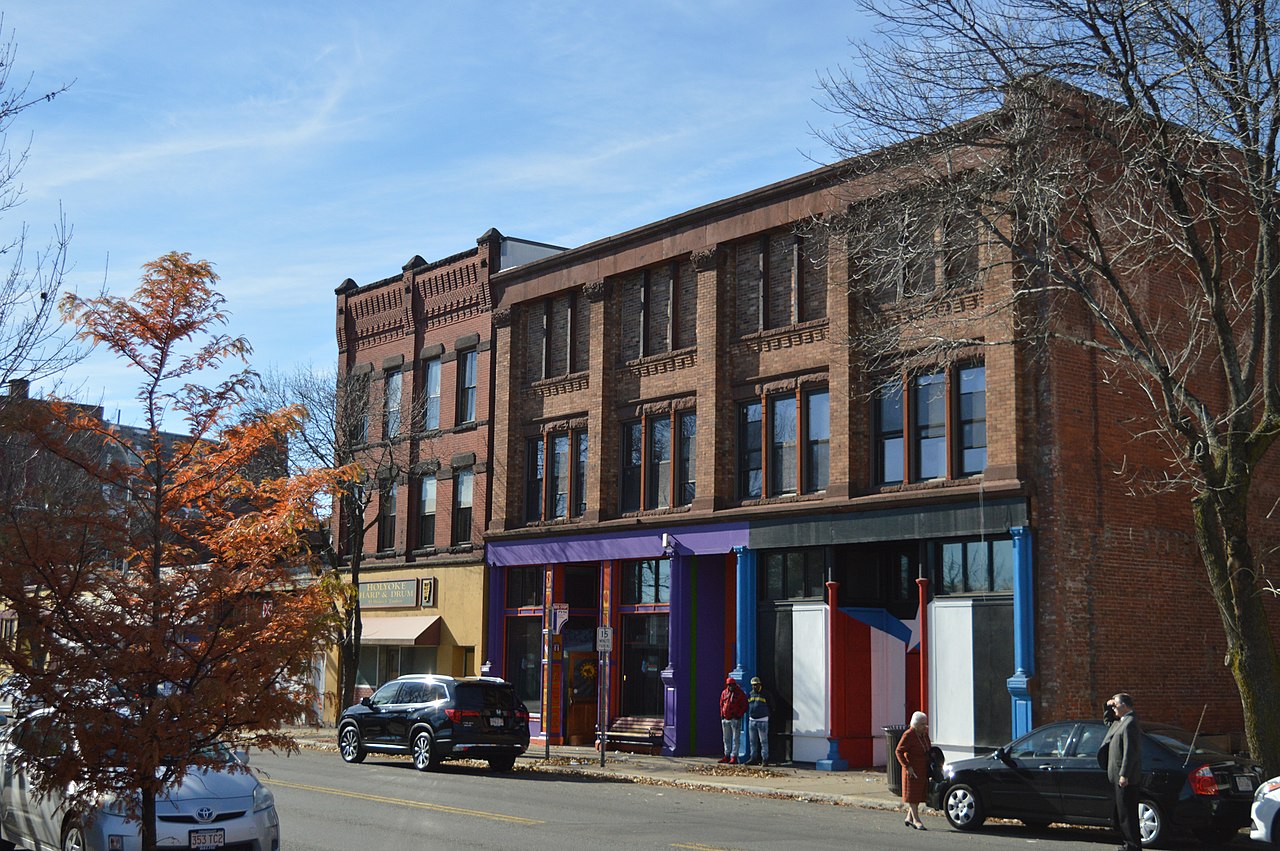 Colorful Puerto Rican piragua cart on a sunny San Juan street with piragüero shaving ice, customers gathered, vibrant scene