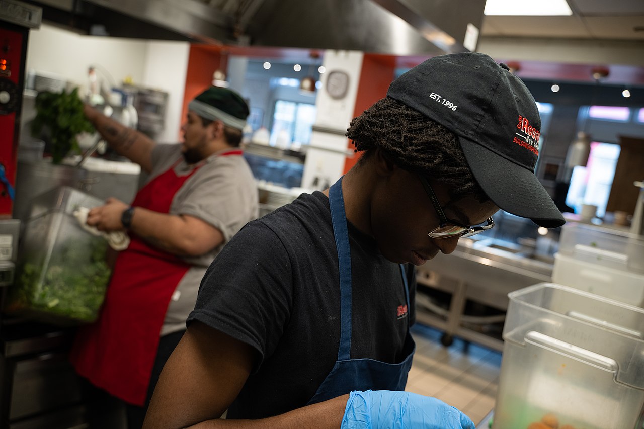 Older Puerto Rican grandmother preparing café criollo using traditional colador method in her kitchen
