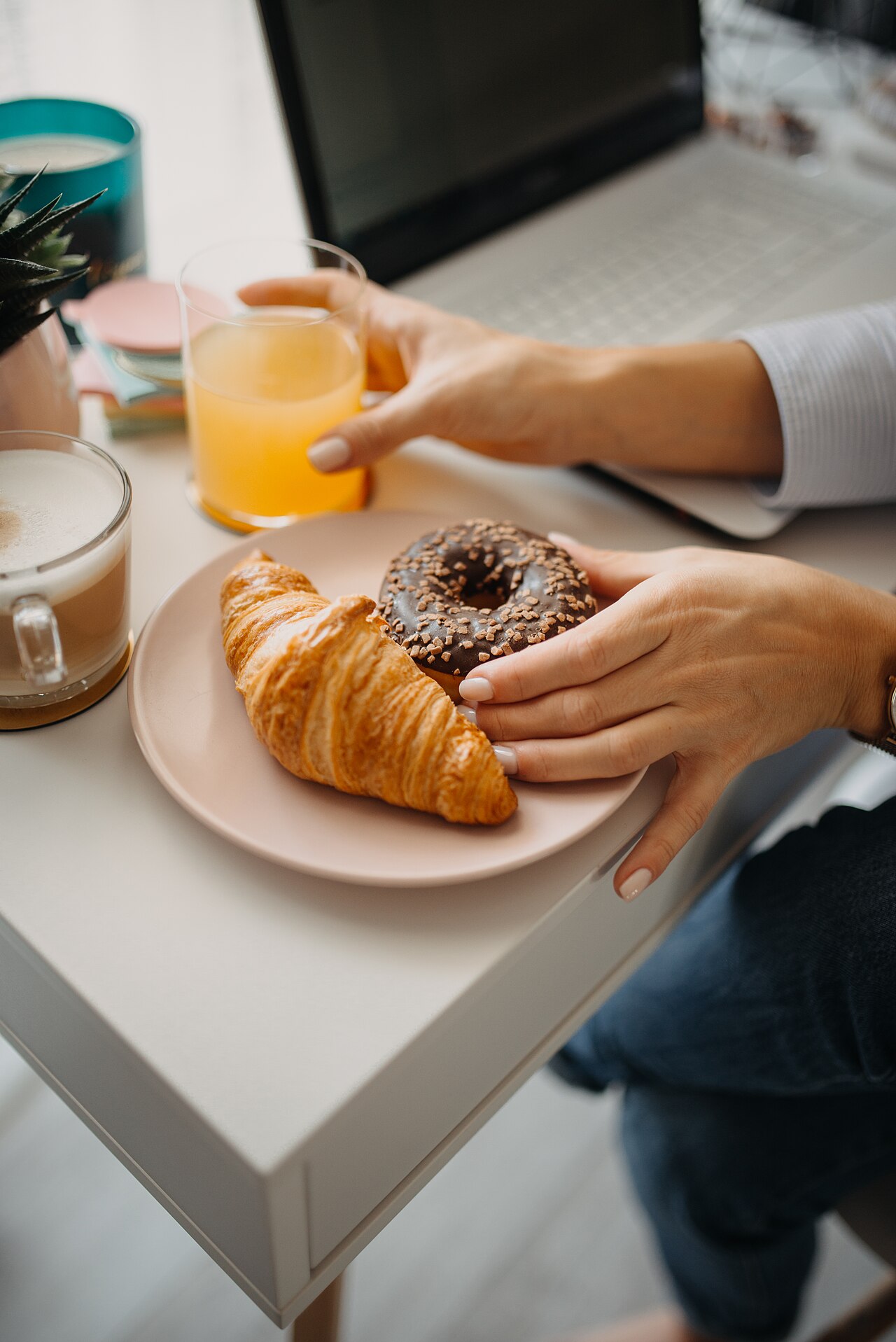 Person enjoying a cup of coffee at a wooden table with morning sunlight, peaceful setting, hands wrapped around ceramic mug