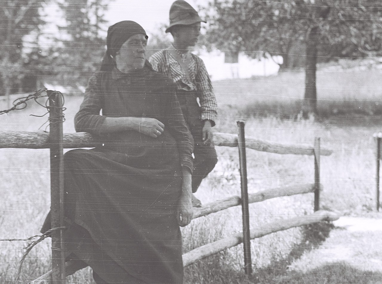 Elderly Puerto Rican woman using pilón in traditional kitchen setting, wearing batik apron, teaching grandchild, multigenerational cultural scene