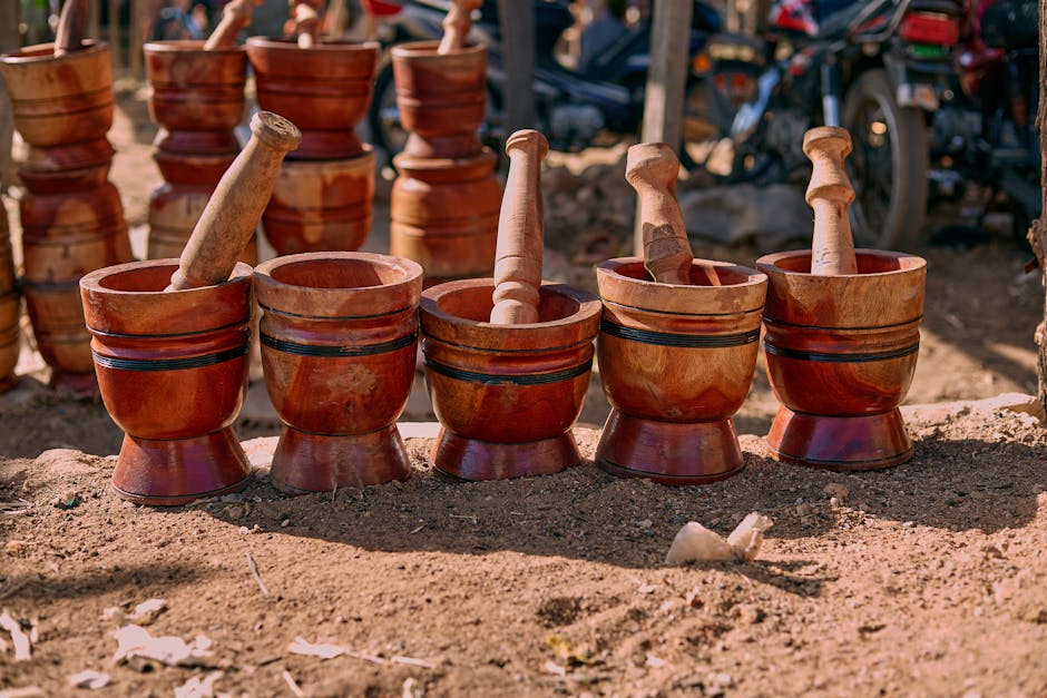 A lineup of handcrafted wooden mortars and pestles displayed on a sunny outdoor market day.