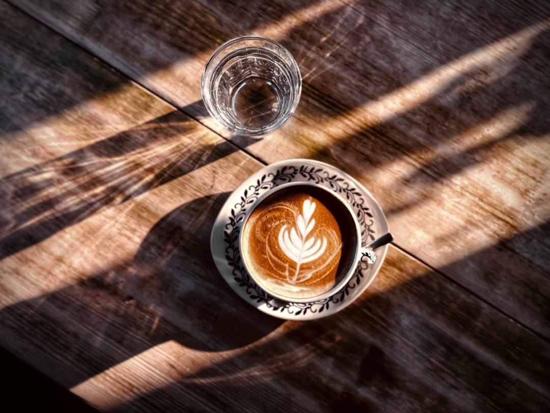 clear glass of water beside coffee cup on wooden surface