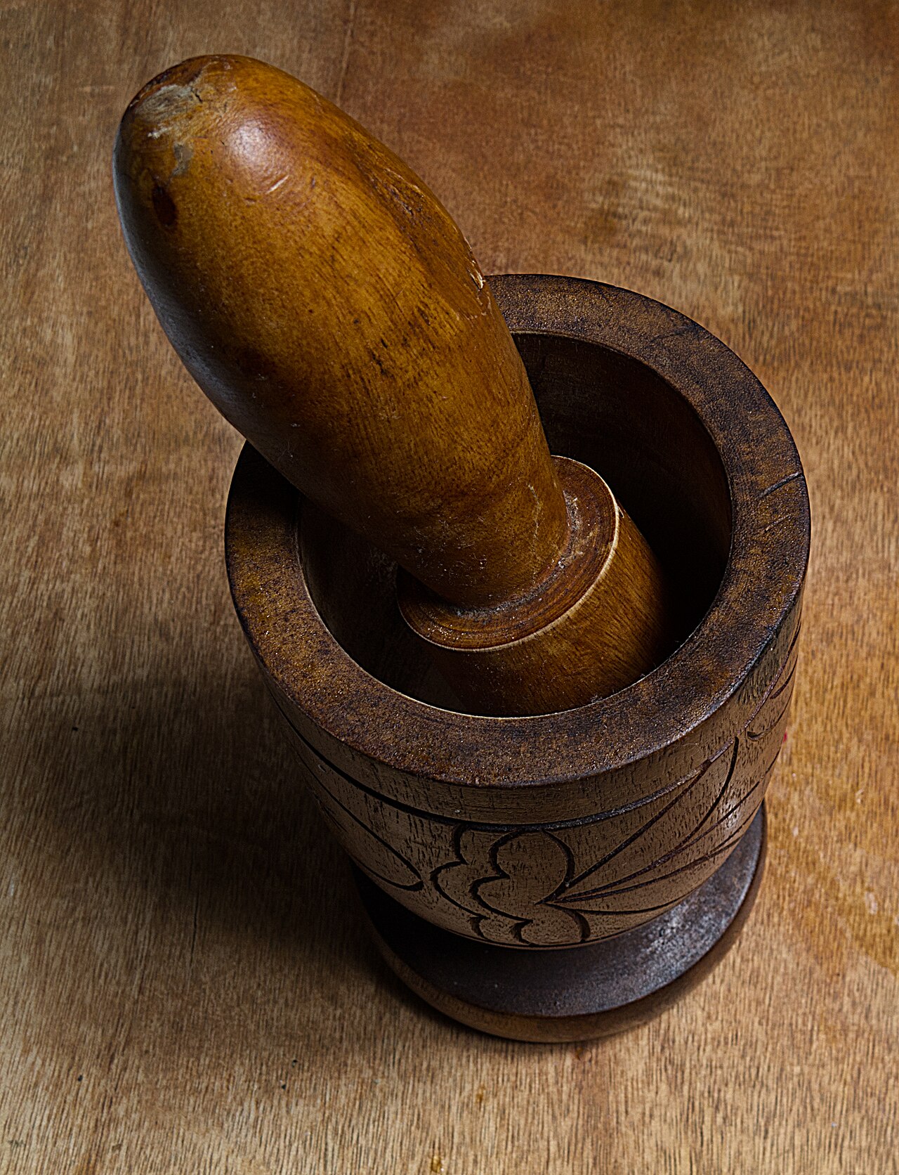 Traditional Puerto Rican wooden pilón (mortar and pestle) with coffee beans inside, on rustic wooden table with Puerto Rican countryside background