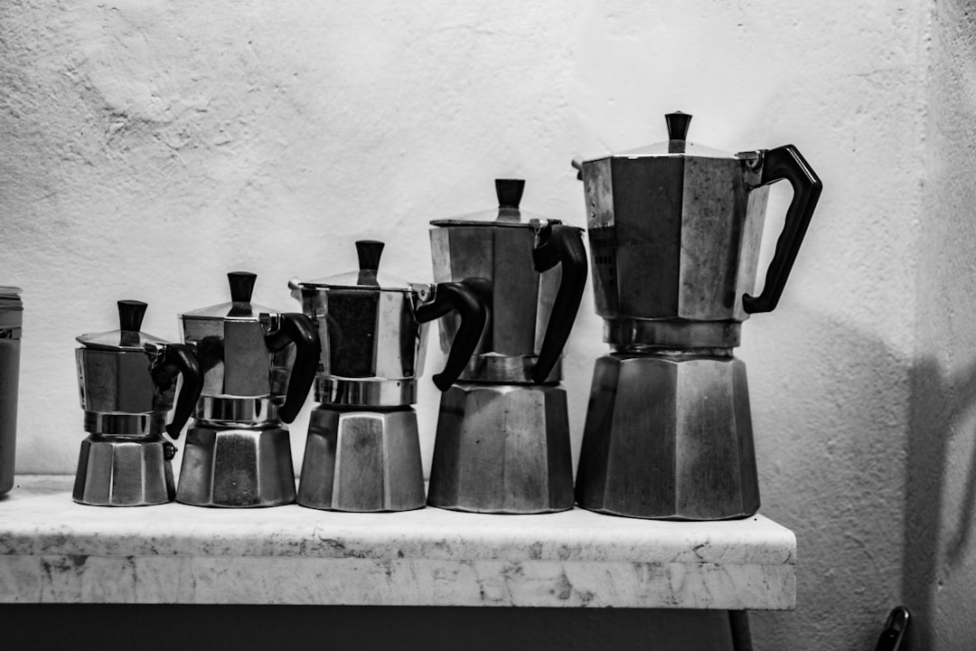 Collection of different sizes of Puerto Rican cafeteras arranged on a kitchen shelf