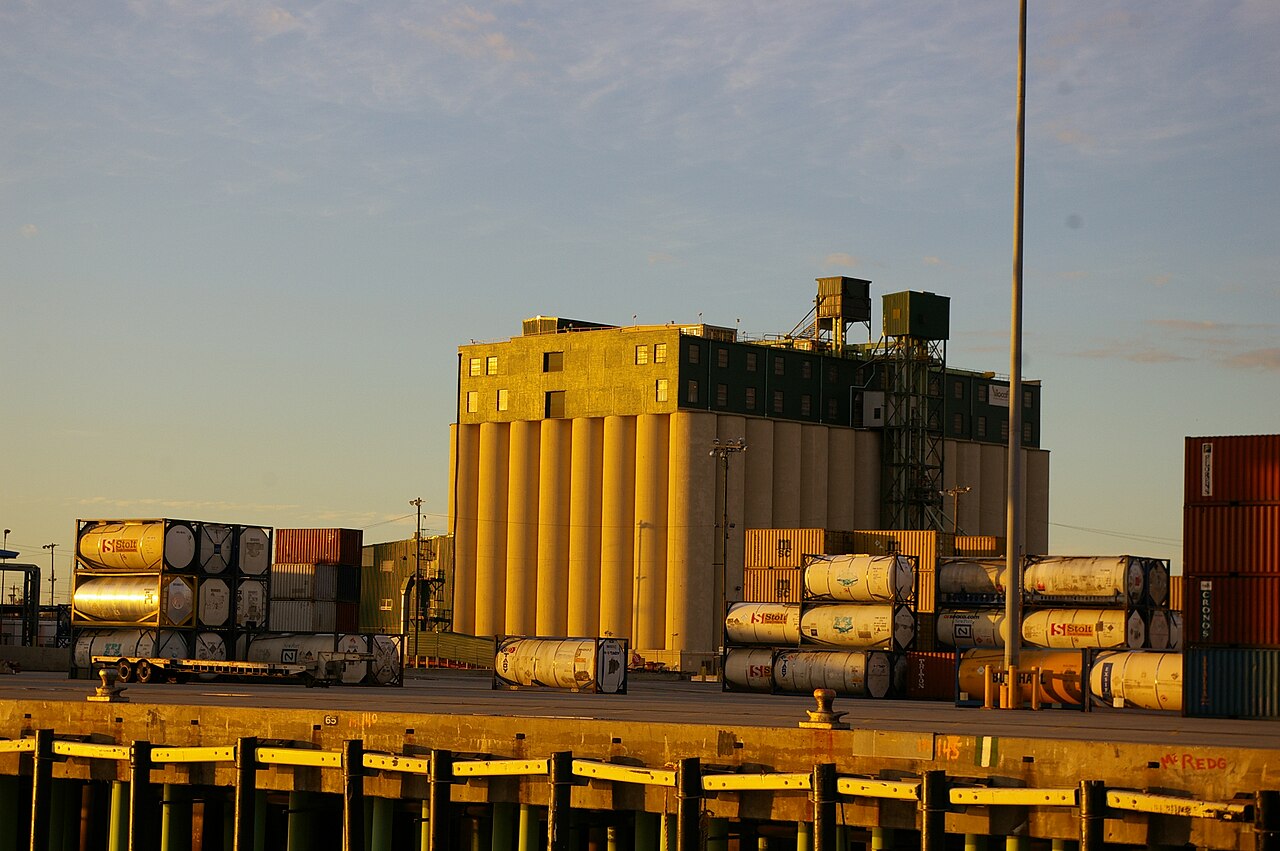 modern coffee processing facility interior in Puerto Rico, stainless steel equipment, technician inspecting coffee at quality control station