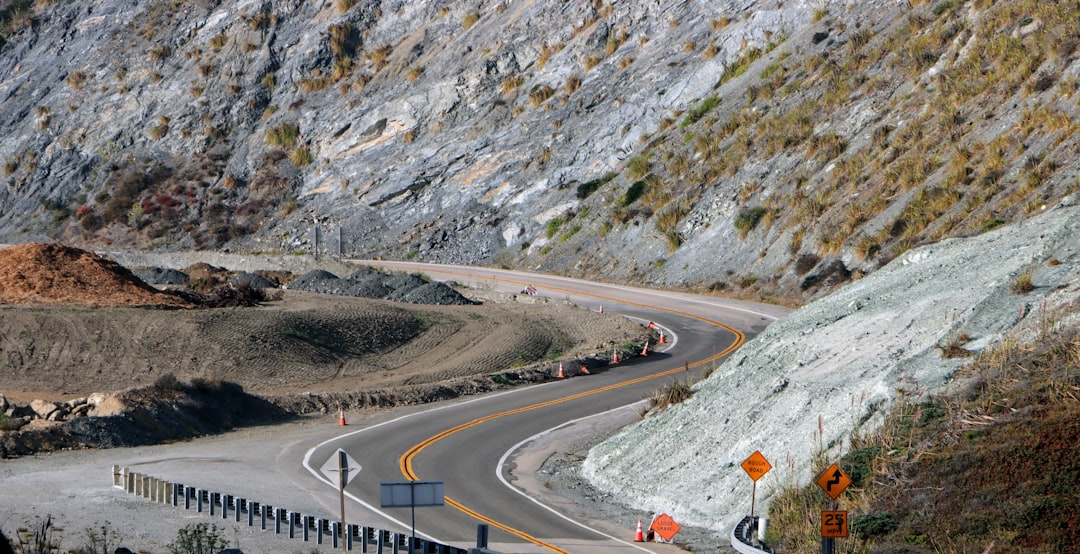 winding mountain road through dense green Puerto Rican cordillera forest, distant view of small farms and red-roofed houses