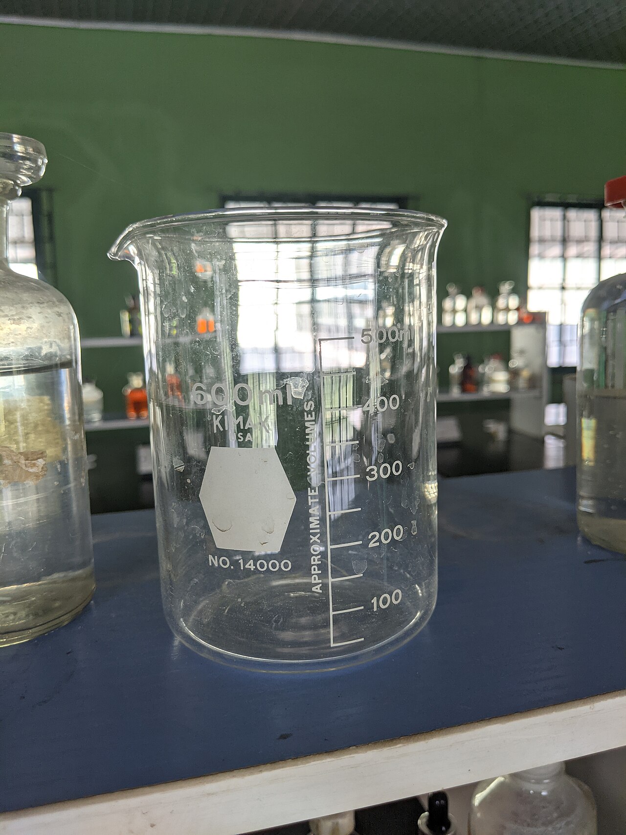 A glass beaker showing a sample of brewed coffee labeled with the proportion of water versus dissolved solids