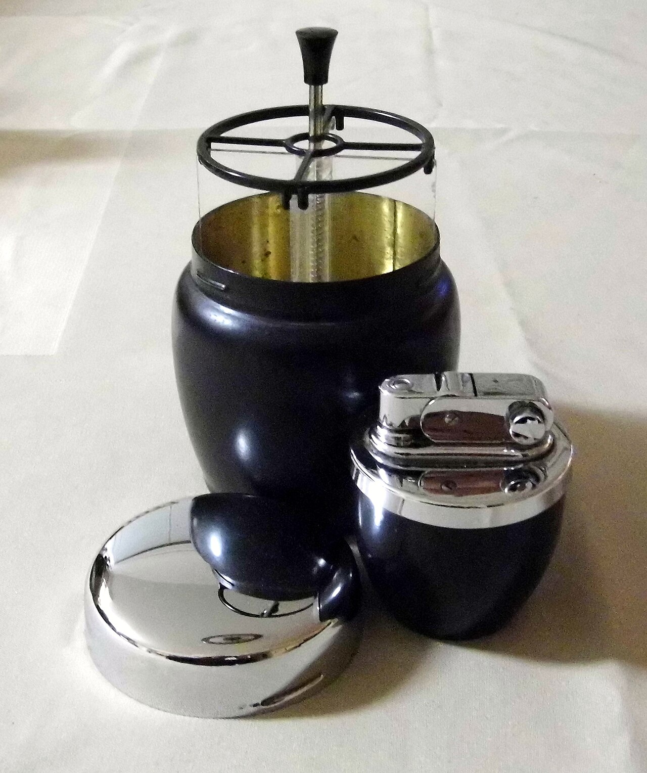 A vintage 1950s-era glass French press alongside a modern stainless steel version, showing the design continuity