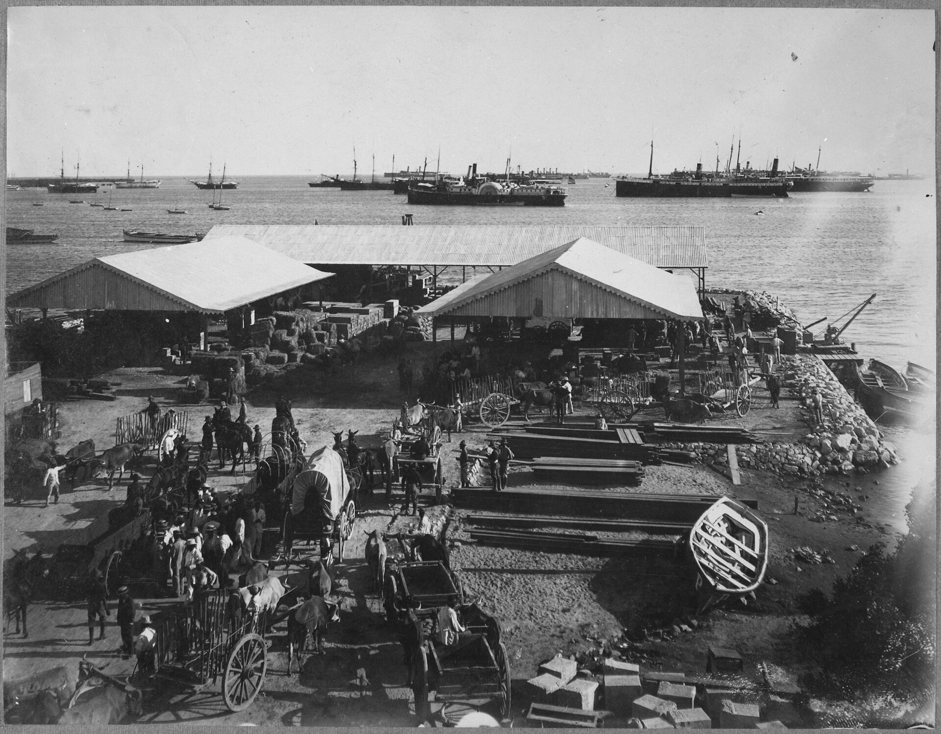 The harbour and principal wharf at Ponce, Puerto Rico, 1899 — cargo sheds, ox-carts and stacked freight on the quay