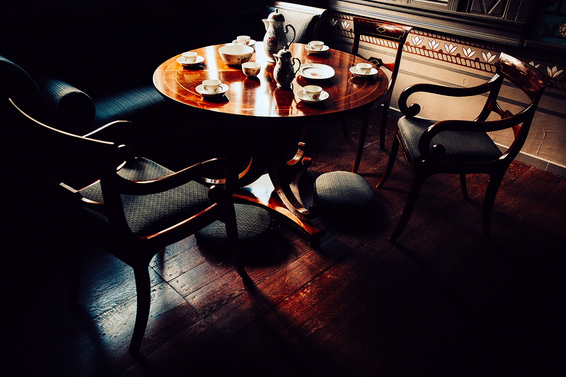 An empty coffee service set out on a round table in raking late-afternoon light