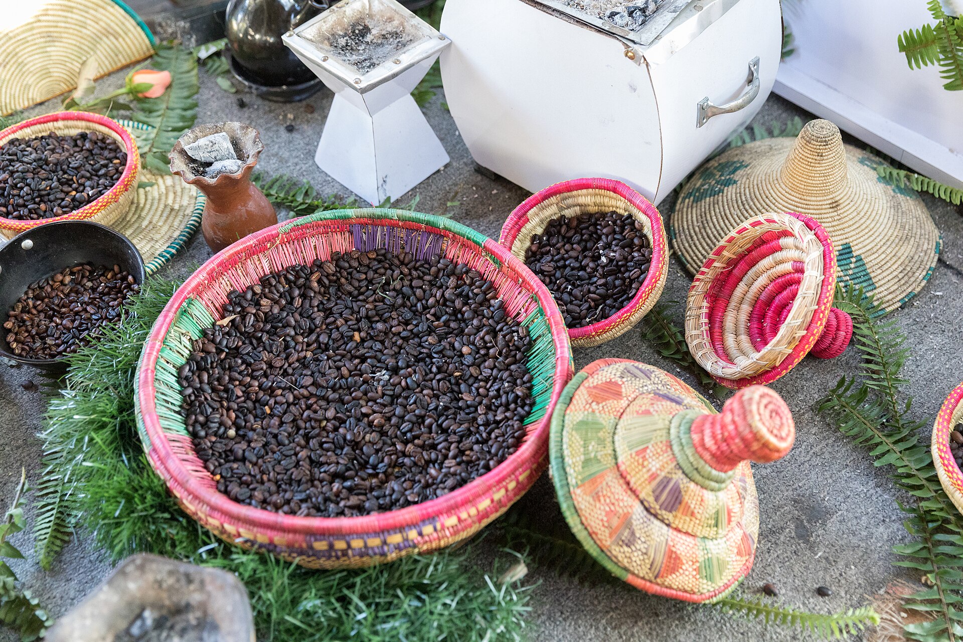 Freshly roasted coffee beans in woven baskets beside a roasting pan in Ethiopia