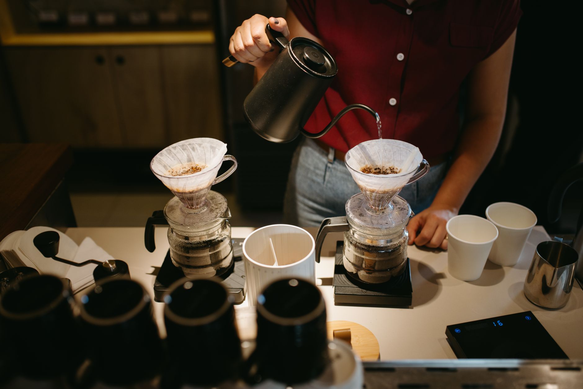 Two pour-over brewers set up side by side on scales with a gooseneck kettle
