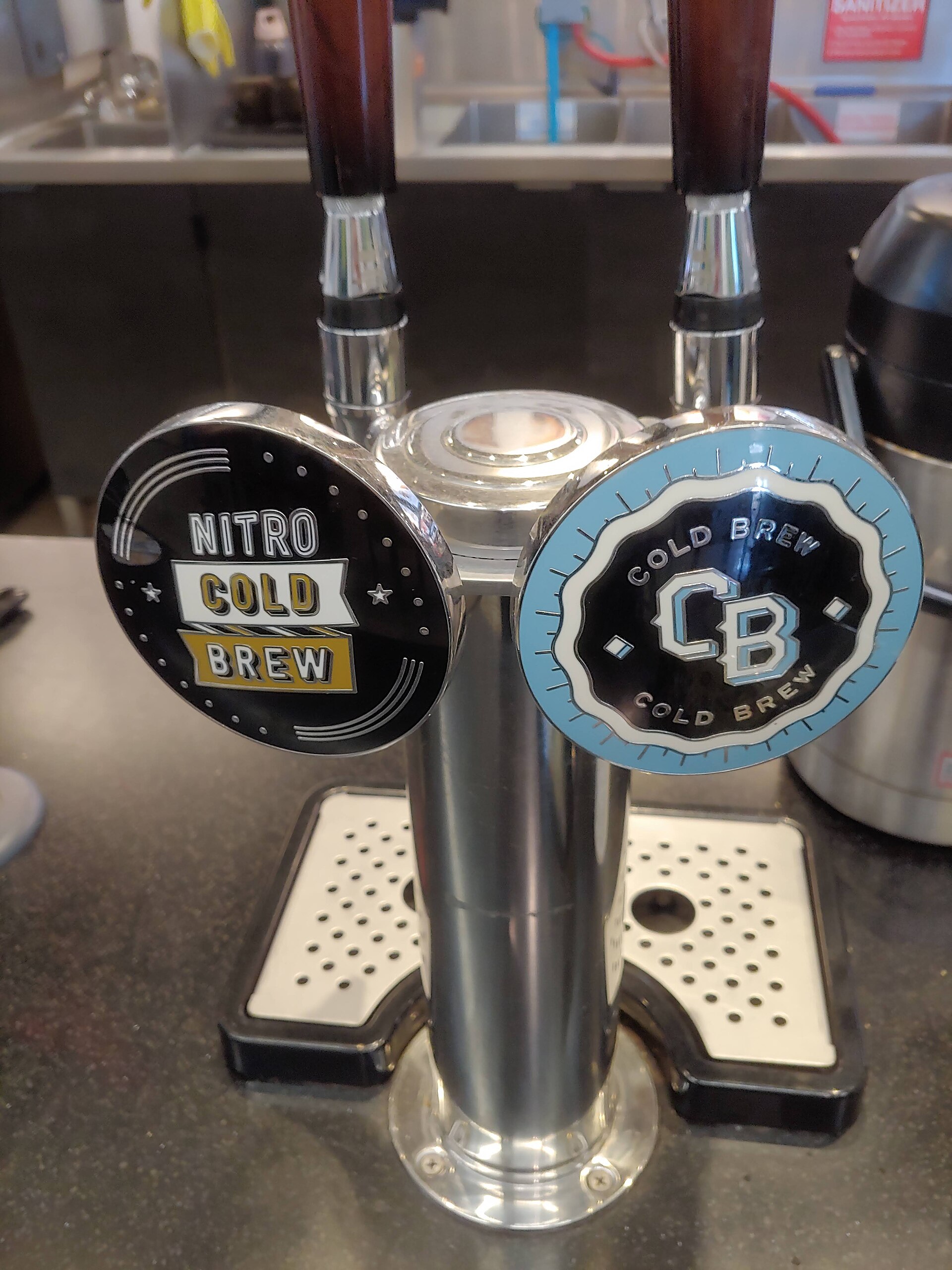 Two taps side by side at a coffee bar, one labelled cold brew and one nitro cold brew