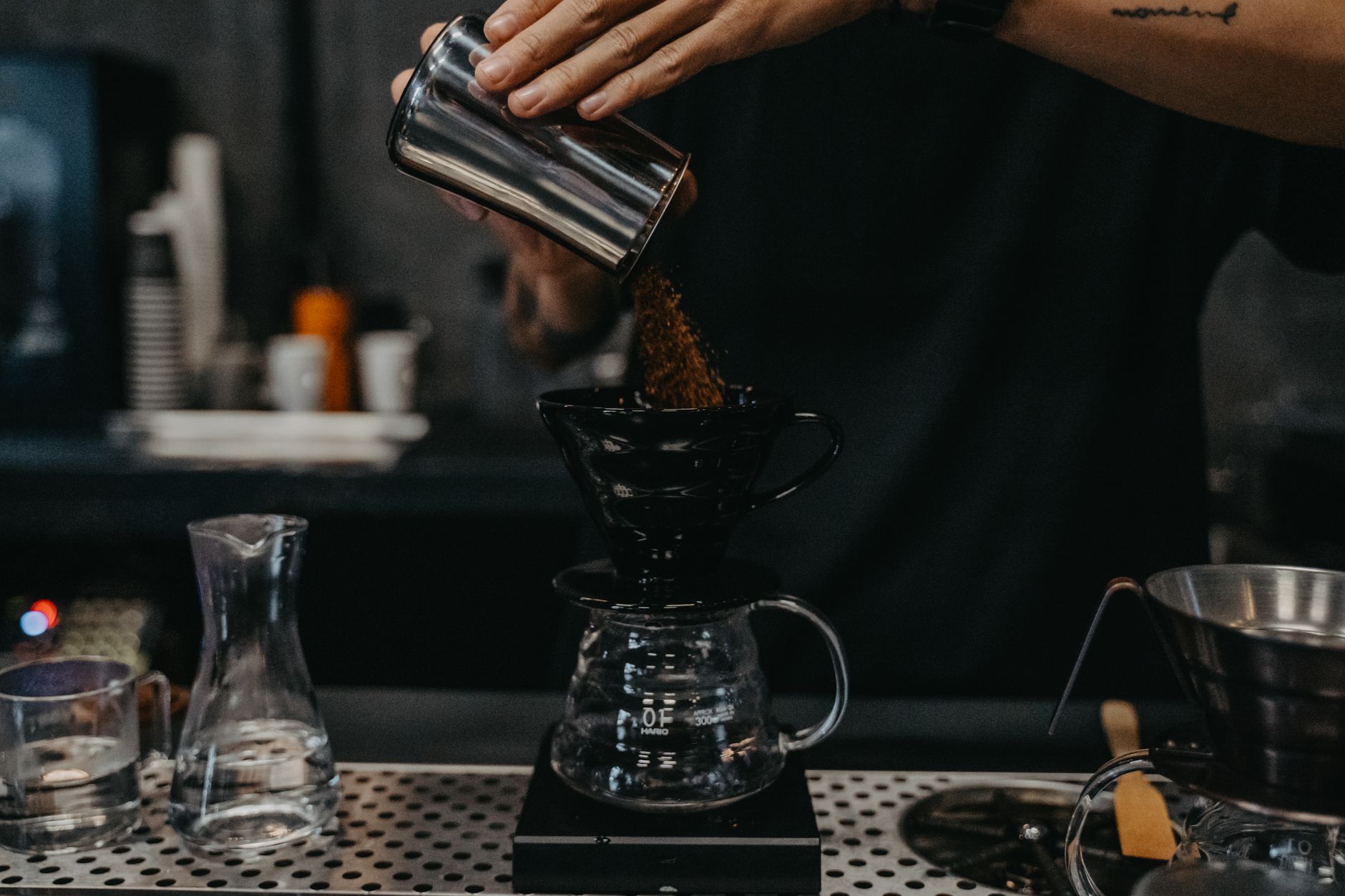 A barista dosing ground coffee for a pour-over brew in a specialty cafe
