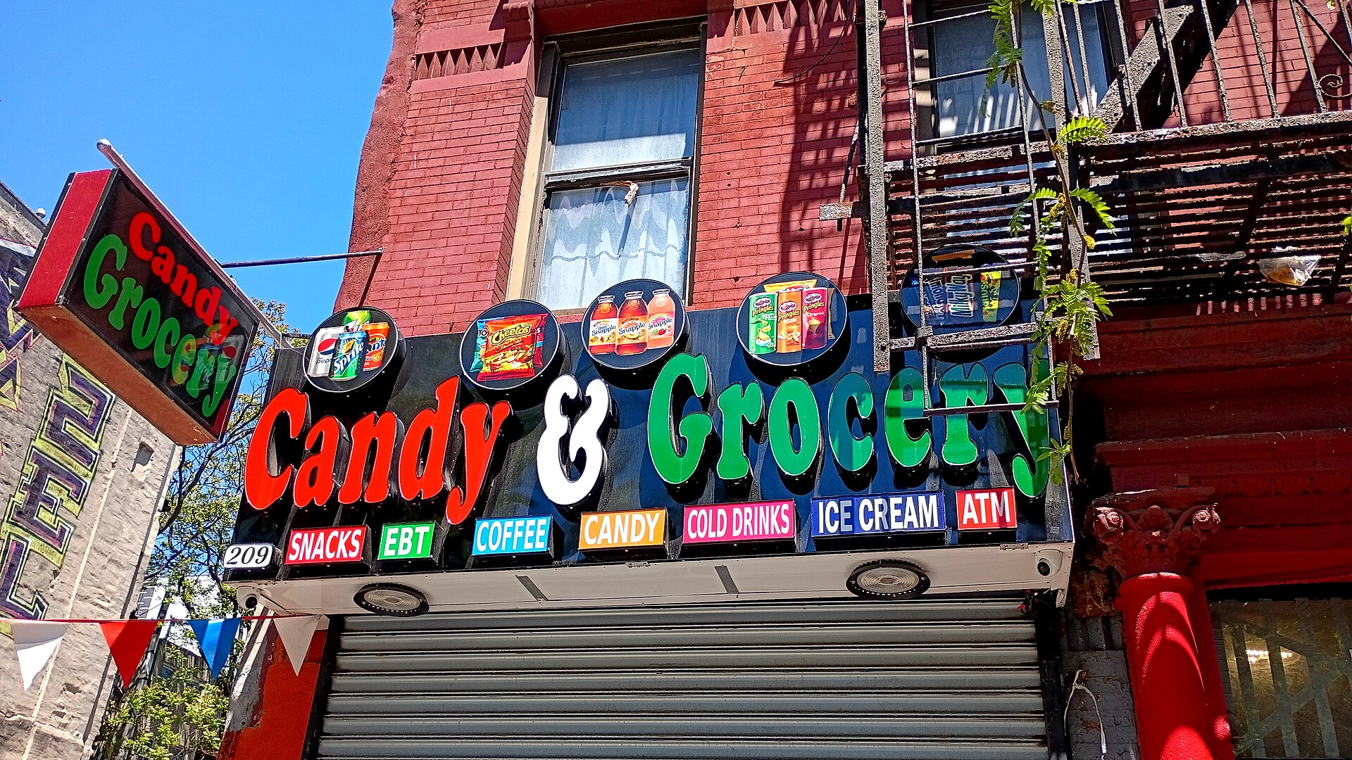 An East Harlem bodega storefront advertising coffee, hung with Puerto Rican flag bunting