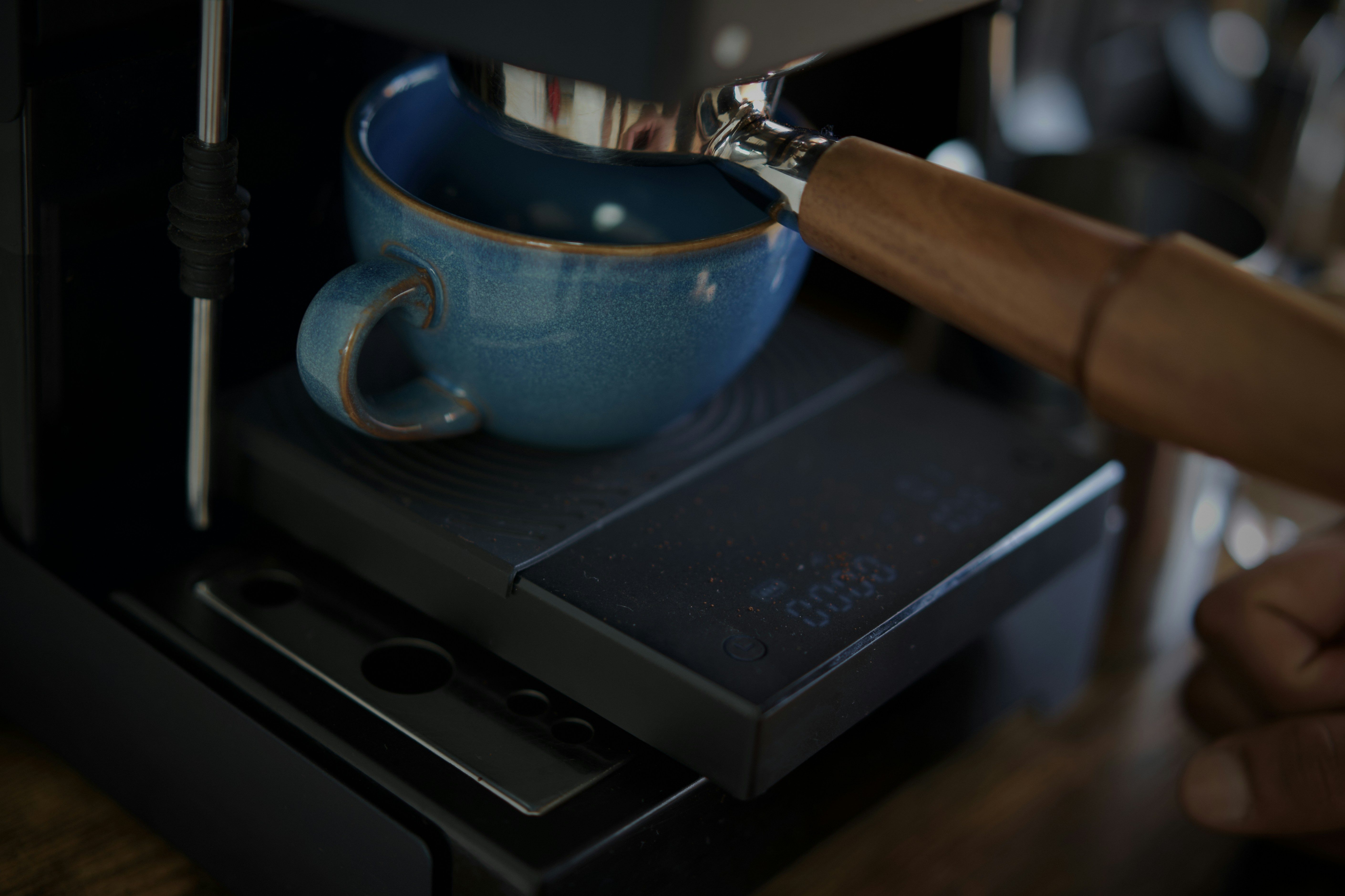 An espresso cup on a digital scale on the drip tray, beneath the portafilter.