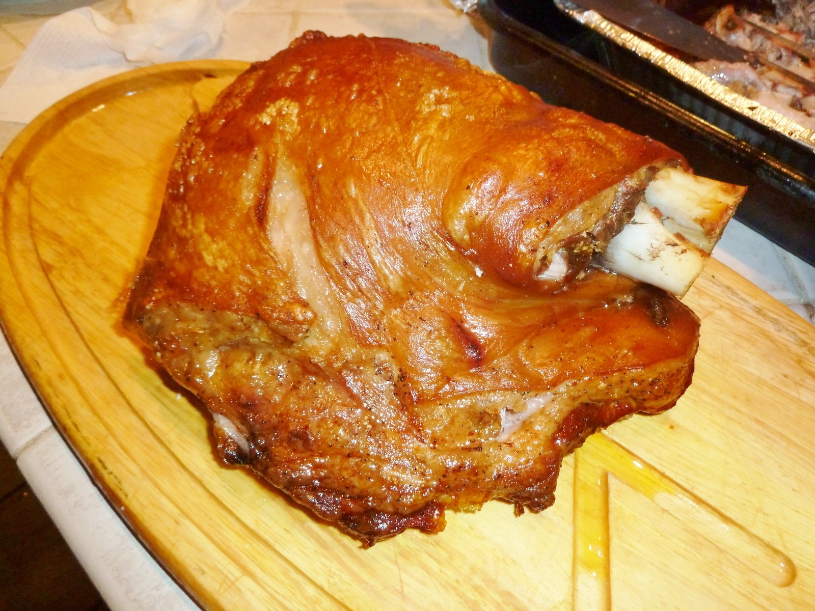 A whole roast pork shoulder on a carving board.